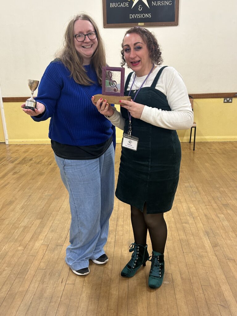 Lesley and Emma from Little Bird Creative at Wadebridge Ambulance Hall, holding awards for More Harmony Women's Barbershop Chorus